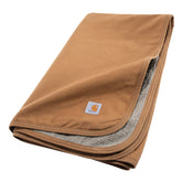 Carhartt Firm Duck Sherpa-Lined Blanket draped on a couch, stays flat and furniture-friendly.