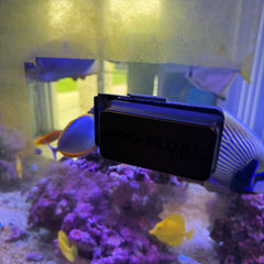 Compact Mag-Float cleaner held in hand along glass edge during cleaning.