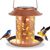 Tepaken dragonfly lantern bird feeder on the ground creates warm garden ambiance.