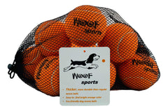 Woof Sports orange-pack dog tennis balls visible in grass for easy fetch