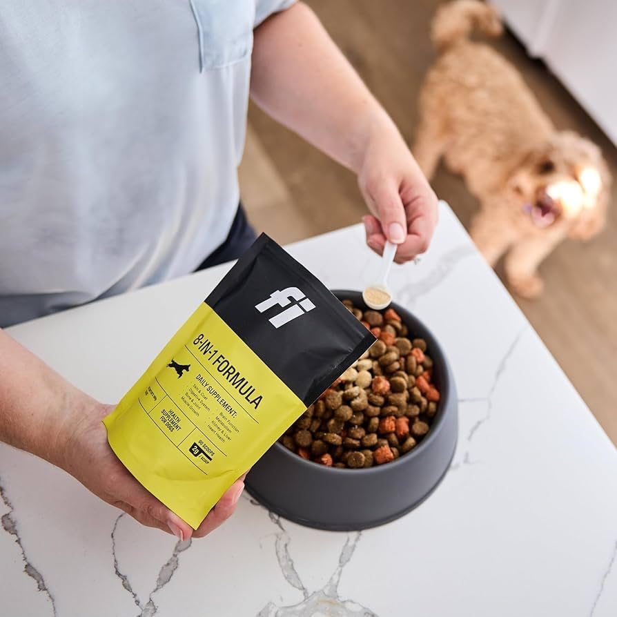 Open Fi container with scoop beside bowl and treats.