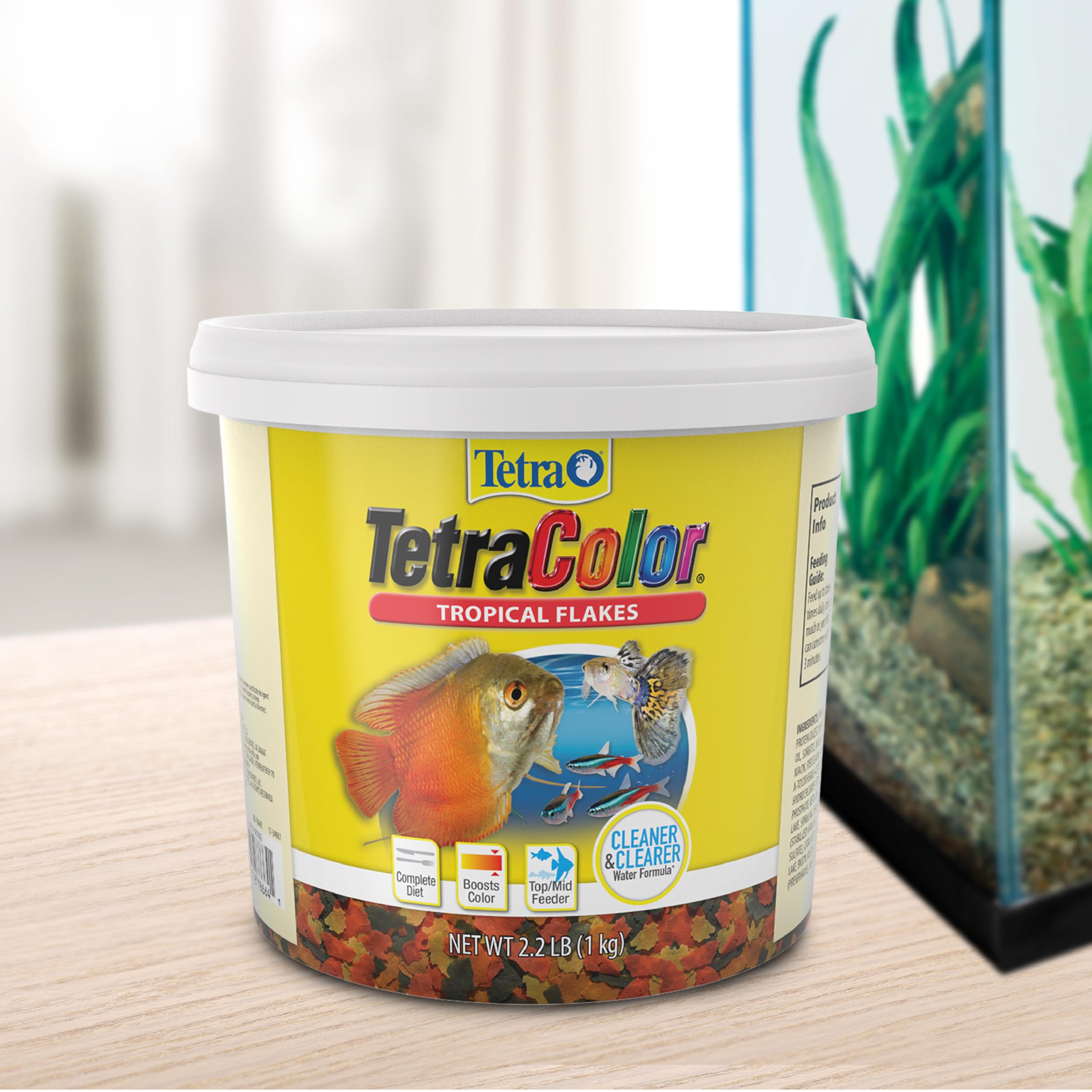 TetraColor Tropical Flakes visible in an aquarium scene with colorful tropical fish.